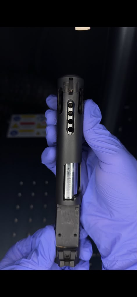 A picture of a gun slide displaying the vertical ports of the gun barrel and slide.
