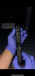 A picture of a gun slide with deep laser engraving work and a cross shaped window cut with vertical inline barrel ports.