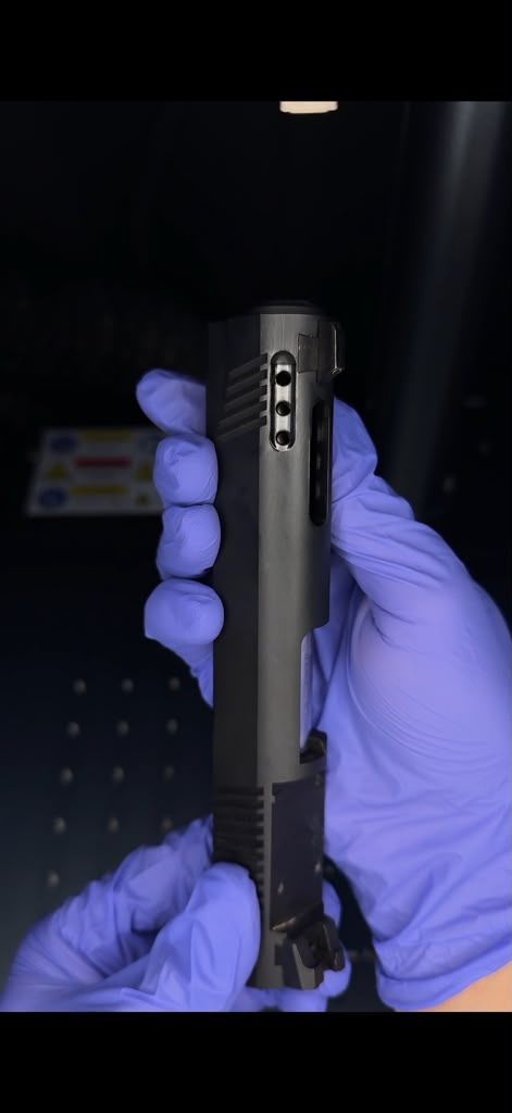 A picture of someone holding a gun slide displaying the porting and slide cut work done to the barrel.
