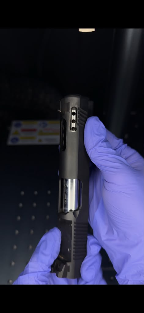 A picture of someone holding a gun slide displaying the porting and slide cut work done to the barrel.